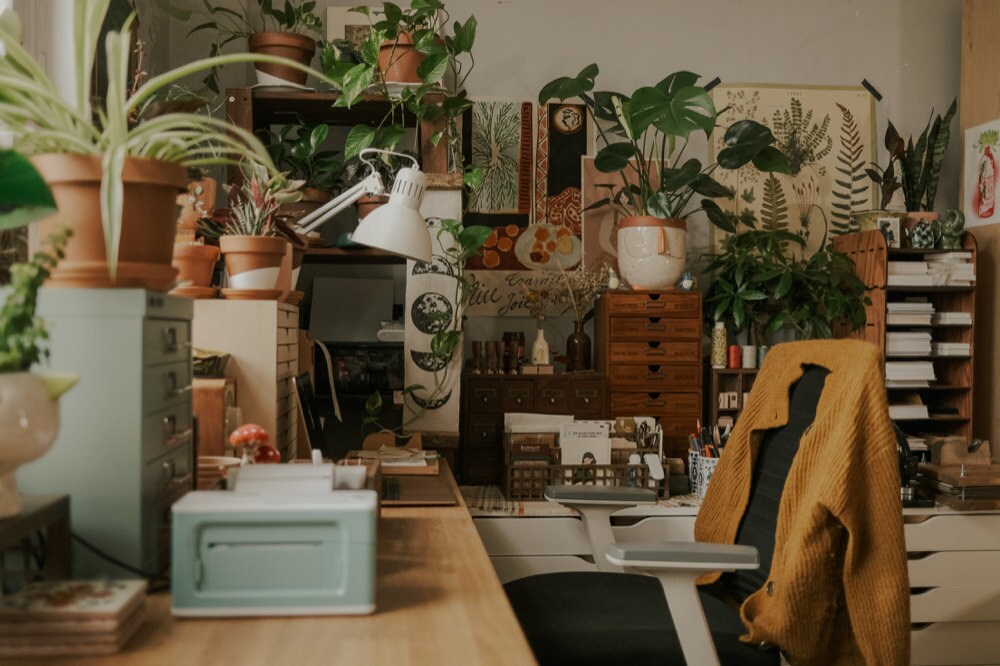 Justine's workspace, filled with pictures and plants.