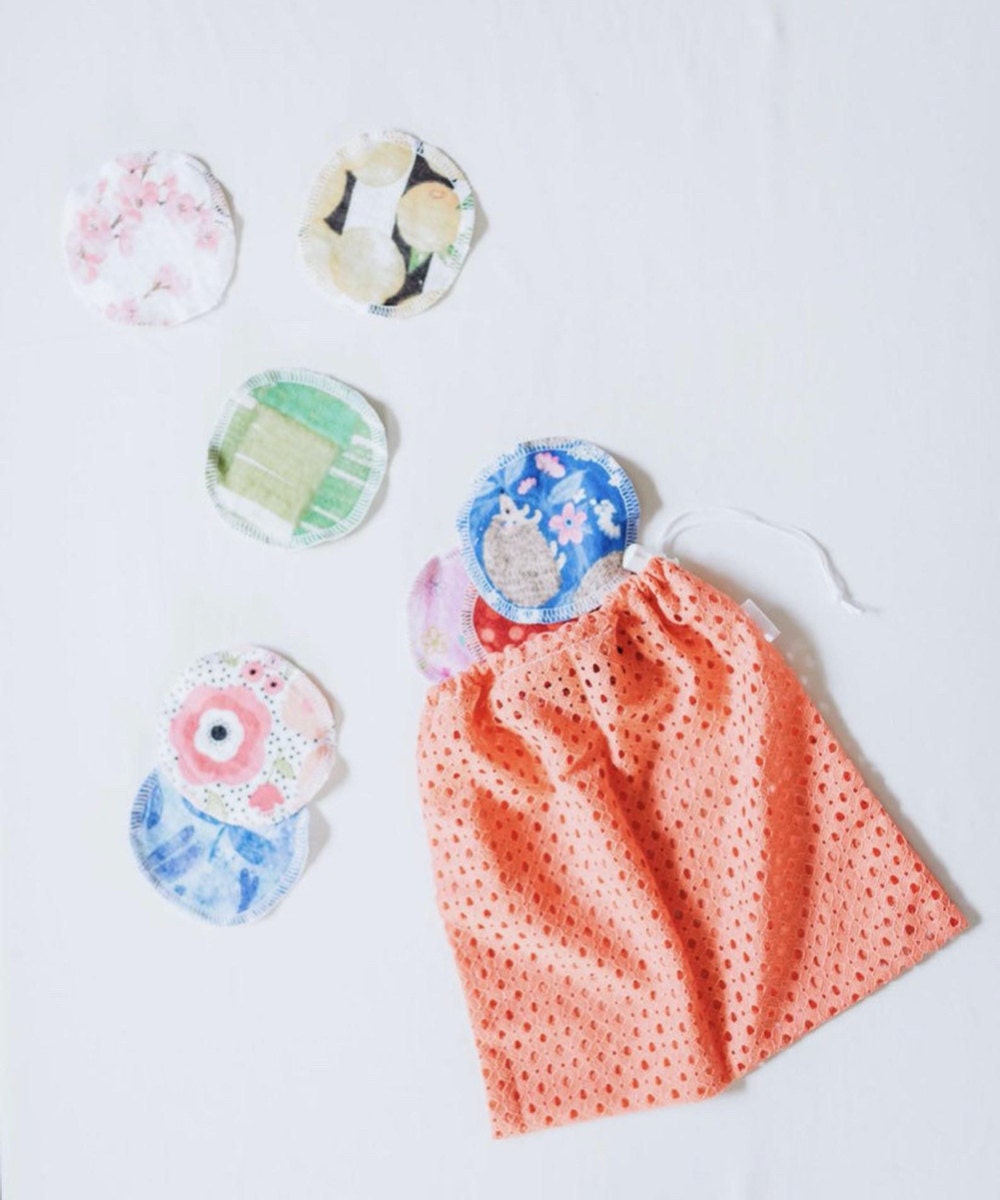 A set of patterned, hand-sewn fleece makeup remover pads pictured spilling out of a fabric bag.