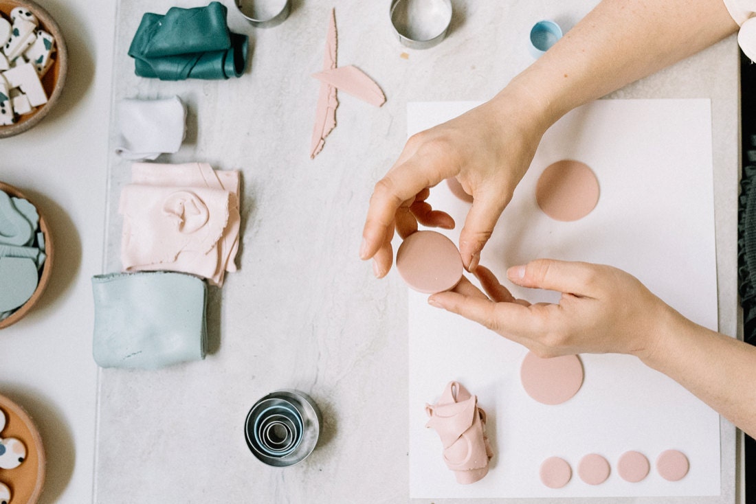 Elyse cuts various sized circles out of blush pink clay