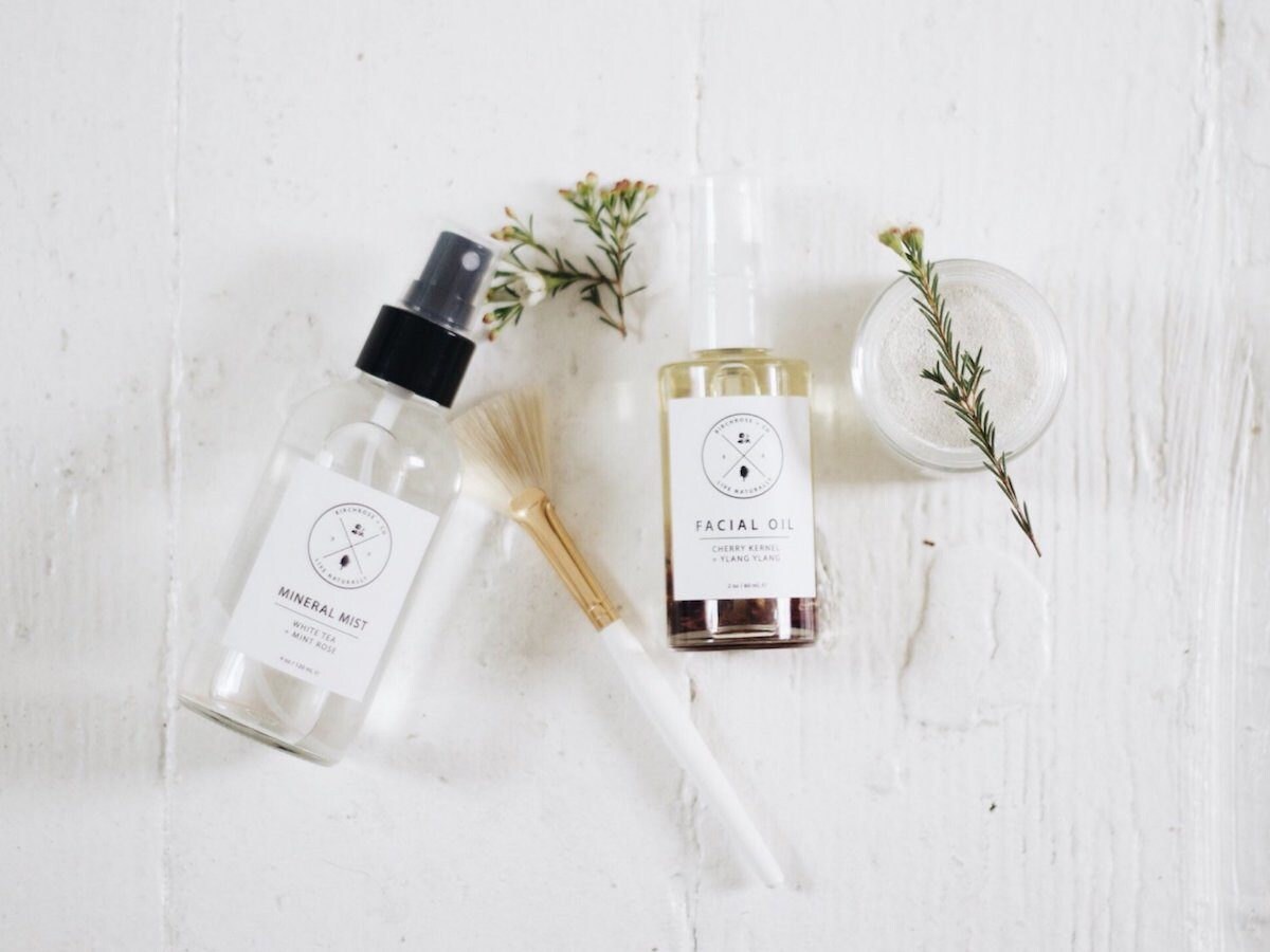 Facial oil and facial mist bottles laid out on a table