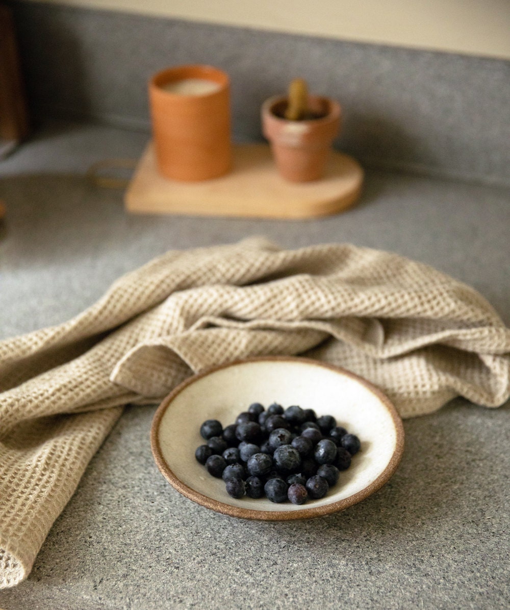 Berries in a bowl arranged on a counter with a tea towel