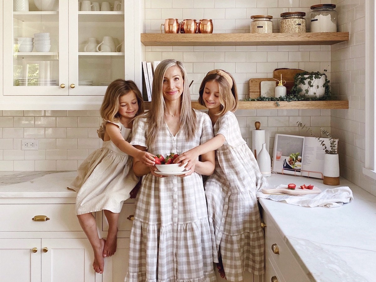 A family photo of Kristine Lee in the kitchen with her daughters, sharing a bowl of strawberries.