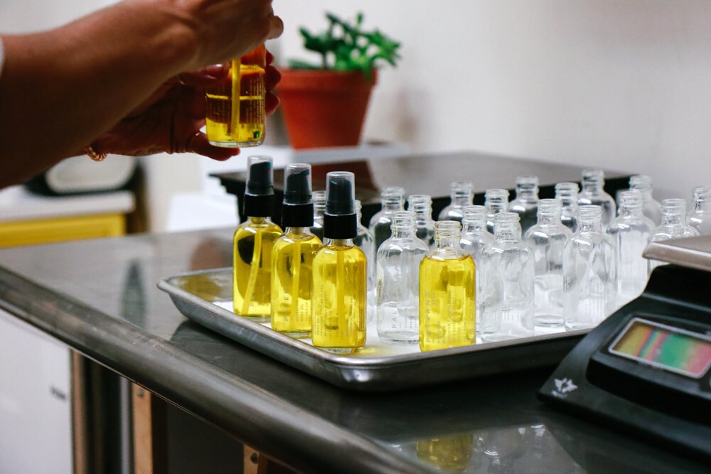 Jessica fills rows of empty bottles with her hydrating body oil.