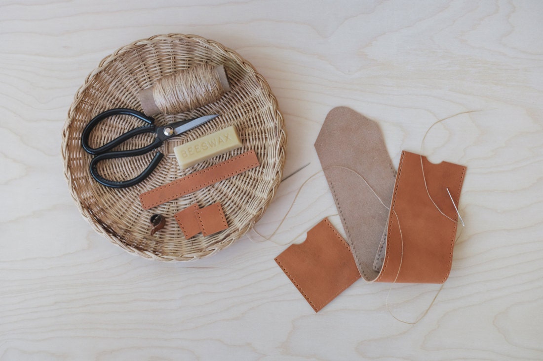 Quynh's materials laid out neatly, including scissors, thread, beeswax, and strips of leather