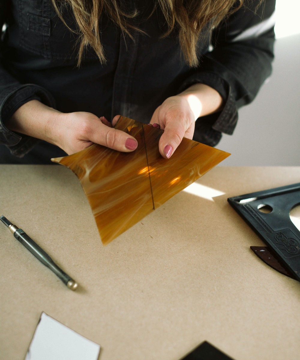 Lauren works on a cut of yellow glass.