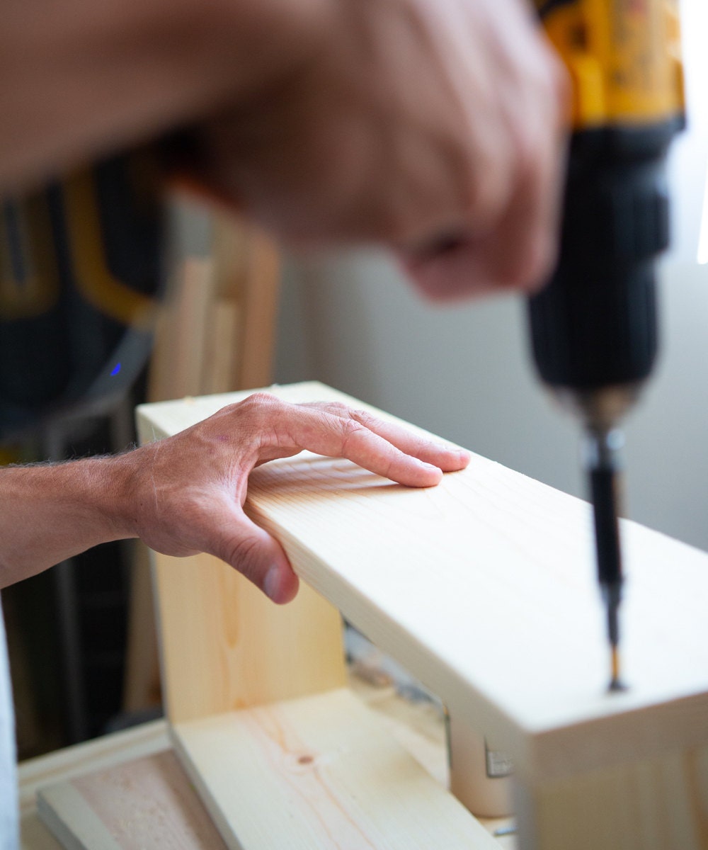 Mike drills holes into a floating shelf.