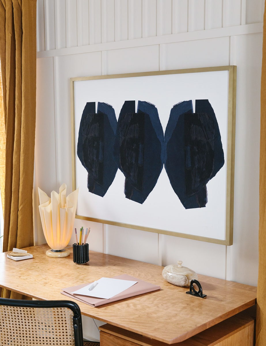 Above the desk is a framed abstract art print with three black circle-like shapes.