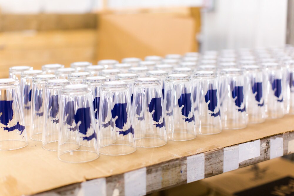 A table filled with rows of neatly organized Michigan state glasses.