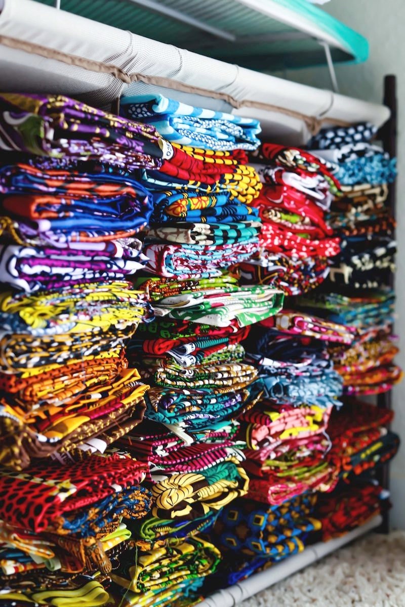 Piles of colorful African wax print fabric in Ade's studio
