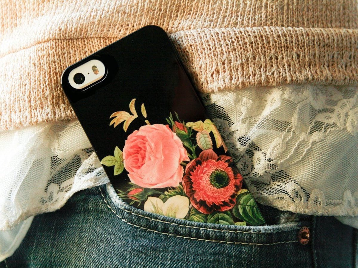 Colorful floral phone case from Joy Merryman peeking out of a pants pocket