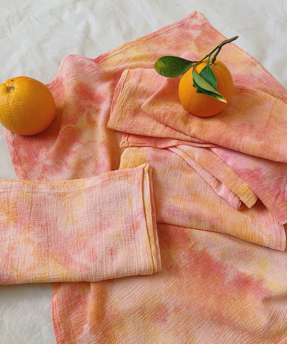 A set of peach-colored tie-dyed cotton napkins.