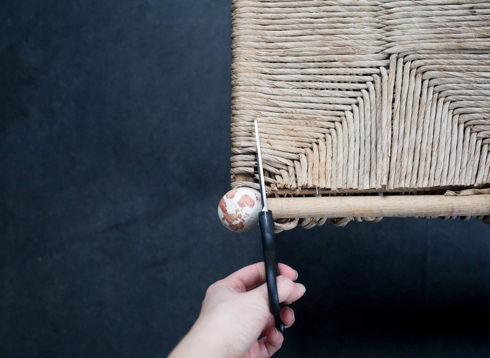 Scissors cutting through woven seat of original stool