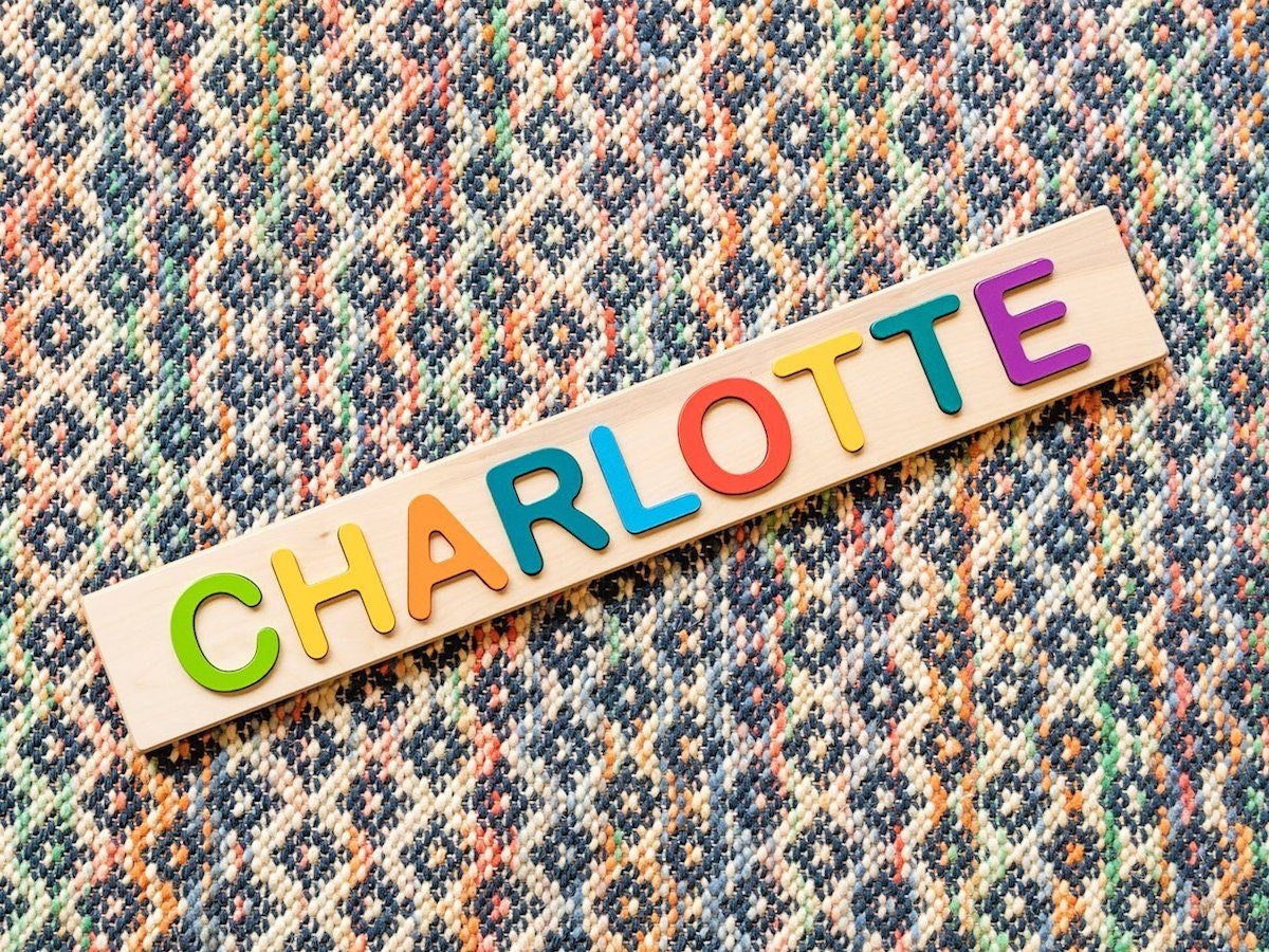 Product photo of a personalized children's name puzzle with wooden rainbow letters.