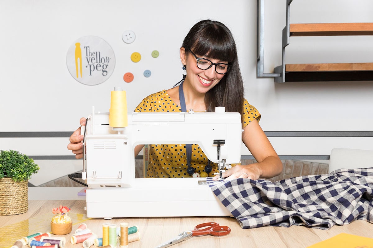 Simona sits at her sewing machine in her studio and works on an item in progress