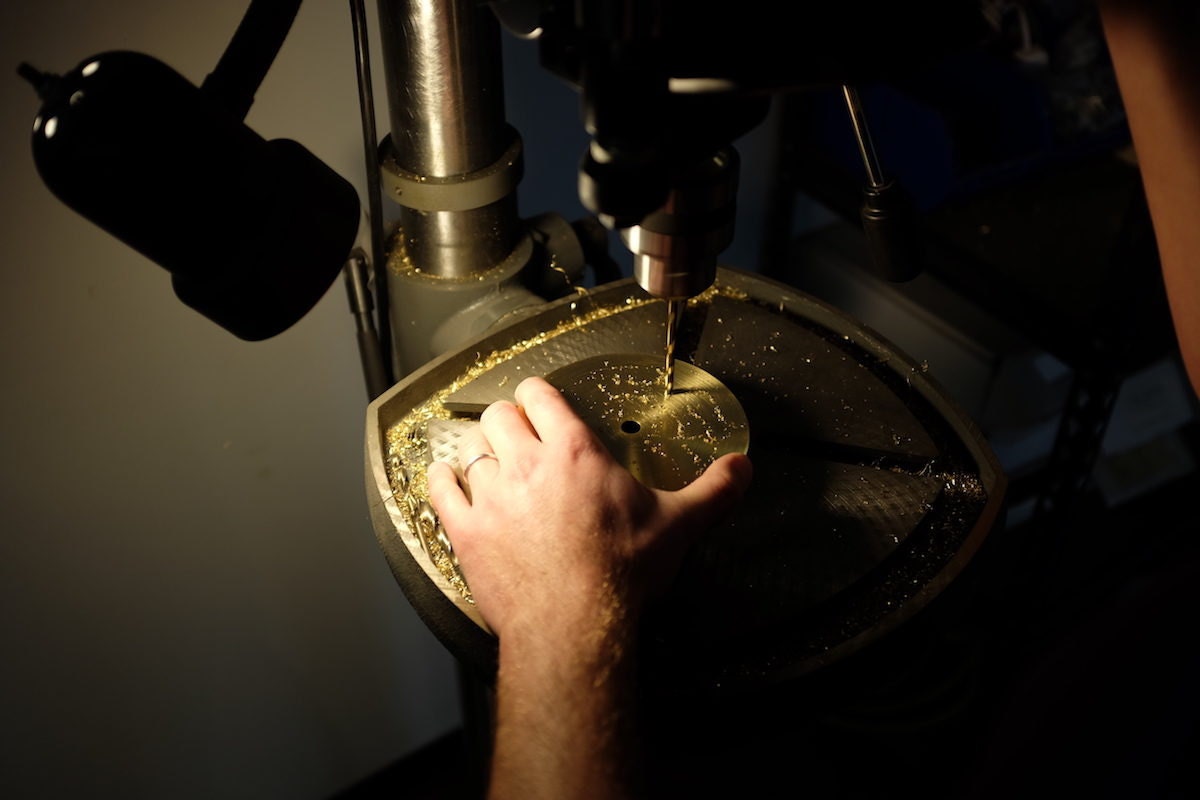 Kyle drills a hole in the brass base for a piece of lighting