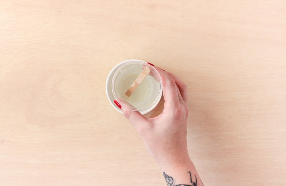 Rachel places her cup of mixed resin into a cup of hot water to allow air bubbles to rise to the surface.