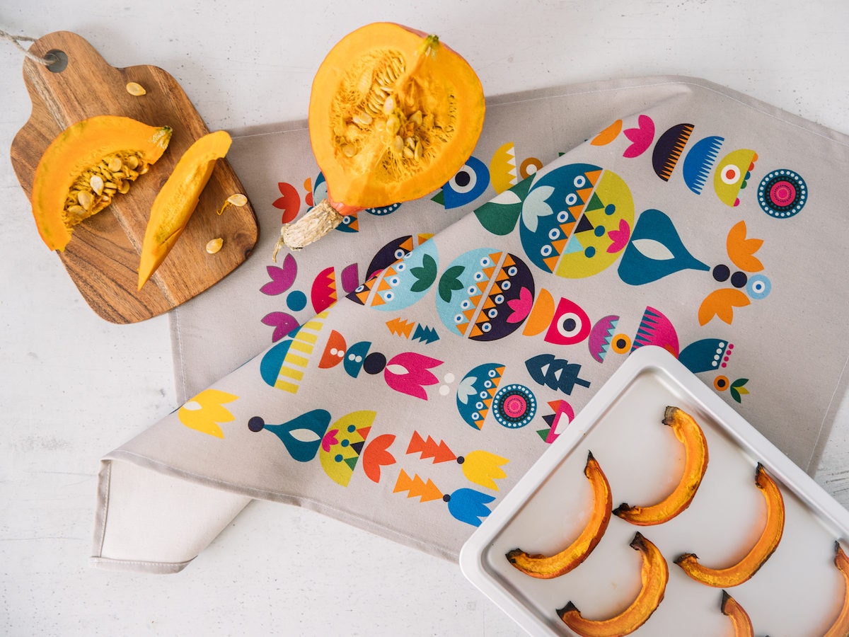 A colorful screen-printed tea towel featuring a Scandinavian-style illustrated pattern, from Softer and Wild.