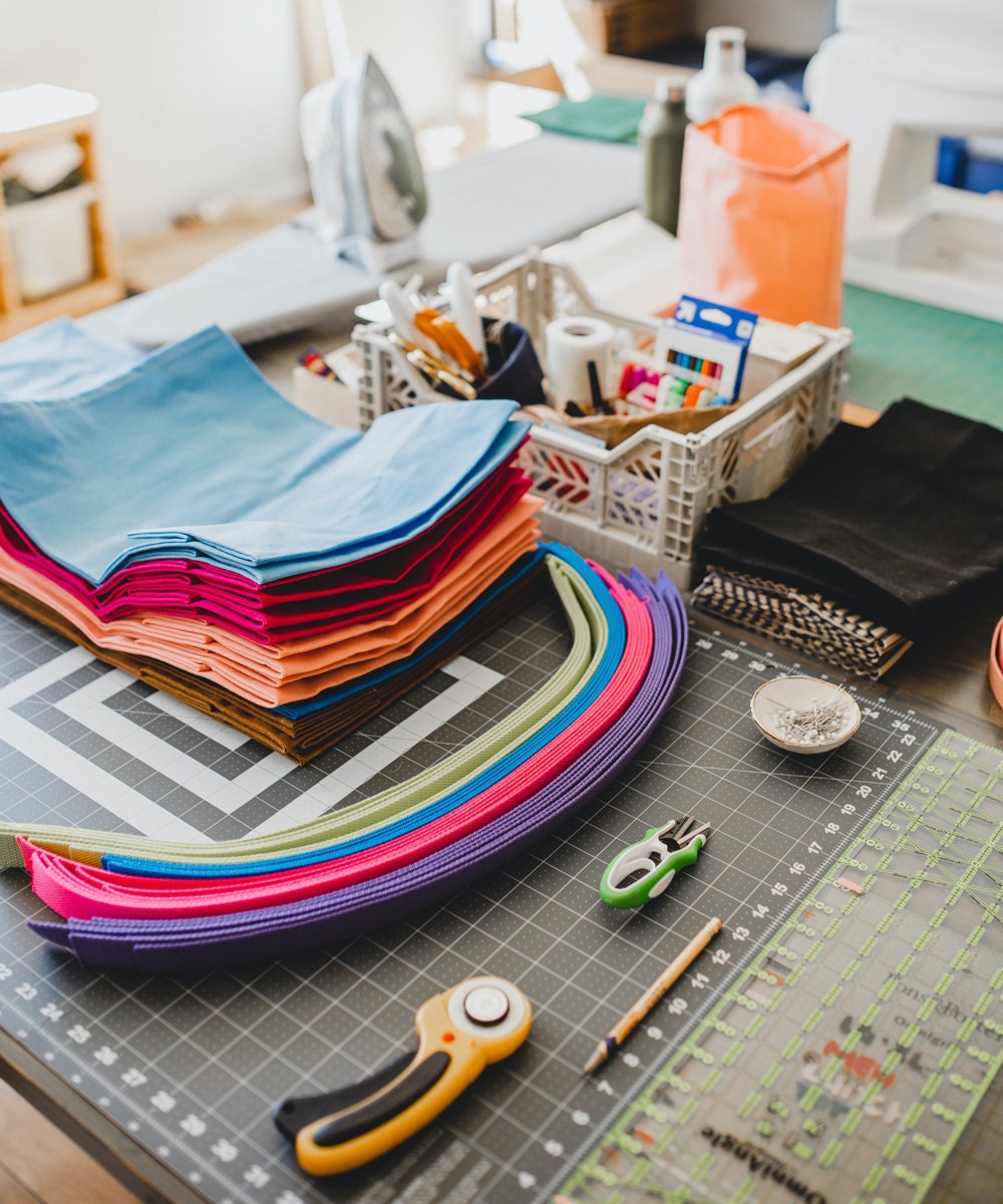 A flat lay of tools and colorful materials for making waxed canvas bags.