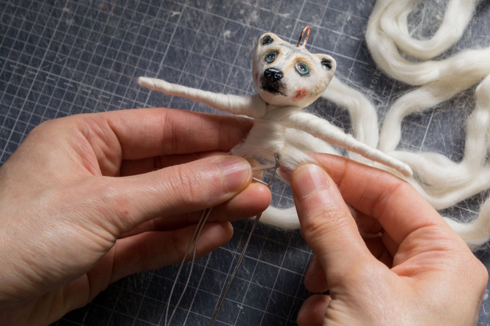 Kayleigh wraps the body of a bear ornament in cotton wool