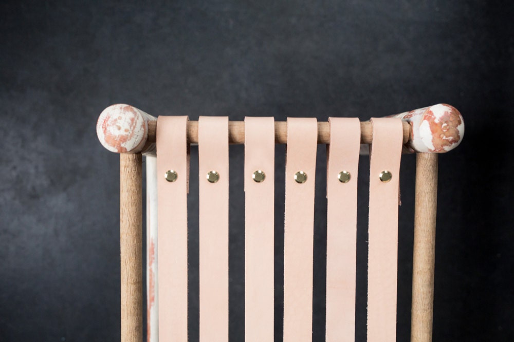 Vintage stool with new leather straps attached to one edge of the frame