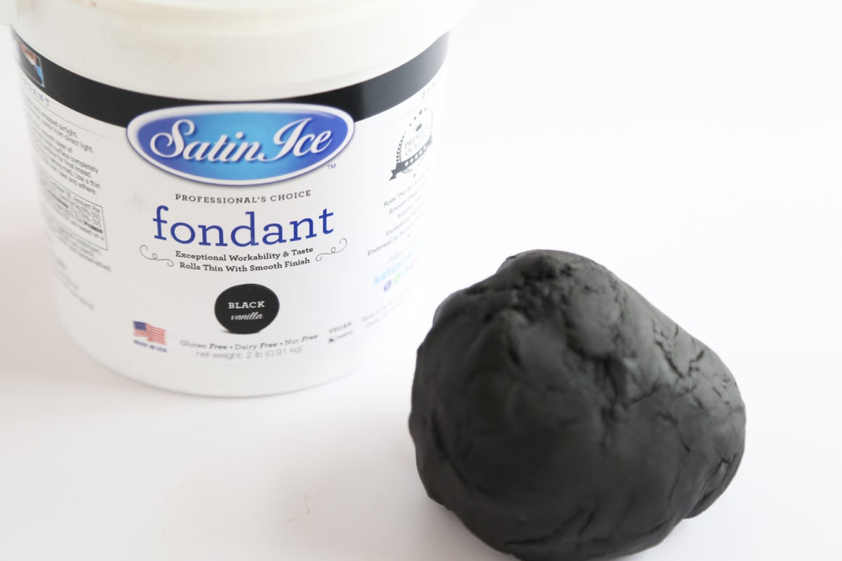 A ball of black fondant icing displayed outside of its container.