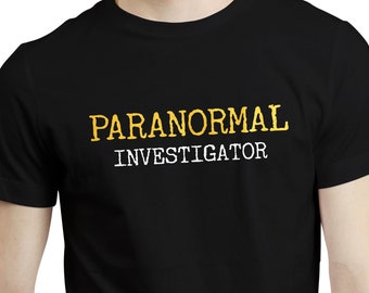 以下が含まれることがあります： 「PARANORMAL INVESTIGATOR」の文字がプリントされた黒いTシャツ。 「PARANORMAL」の文字は黄色で、「INVESTIGATOR」は白です。 このTシャツはクルーネックで半袖です。