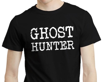 Może przedstawiać: Czarny t-shirt z napisem "GHOST HUNTER" w postarzanych białych literach. Koszulka z okrągłym dekoltem wykonana jest z miękkiego materiału. Tekst jest wyśrodkowany na klatce piersiowej.