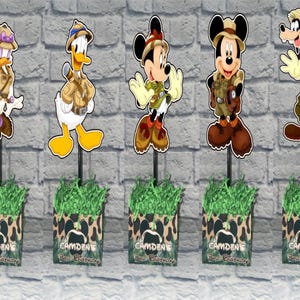 Puede incluir: Cinco centros de mesa decorativos con los personajes de Disney Daisy, Donald, Minnie, Mickey y Goofy con ropa de safari. Cada personaje se apoya en una base con hierba de papel verde y el texto Camden's 3rd Birthday.