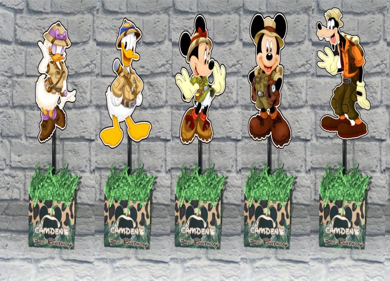 Puede incluir: Cinco centros de mesa decorativos con los personajes de Disney Daisy, Donald, Minnie, Mickey y Goofy con ropa de safari. Cada personaje se apoya en una base con hierba de papel verde y el texto Camden's 3rd Birthday.