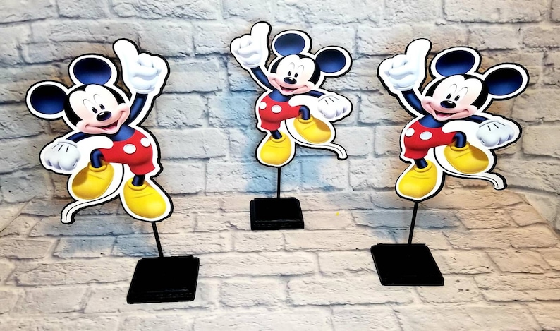 May include: Three Mickey Mouse centerpieces, each featuring a cartoon image of Mickey Mouse in his signature red shorts and yellow shoes, with a black base.