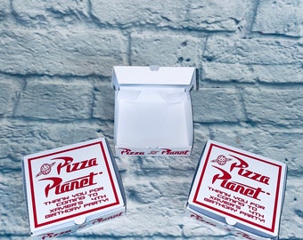 May include: Three white pizza boxes with red and black text that reads "Pizza Planet". The boxes have a thank you message for coming to Xavier's 4th birthday party.