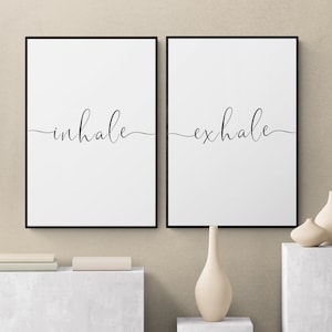 May include: Two black framed prints with white backgrounds and the words "inhale" and "exhale" in black cursive script.