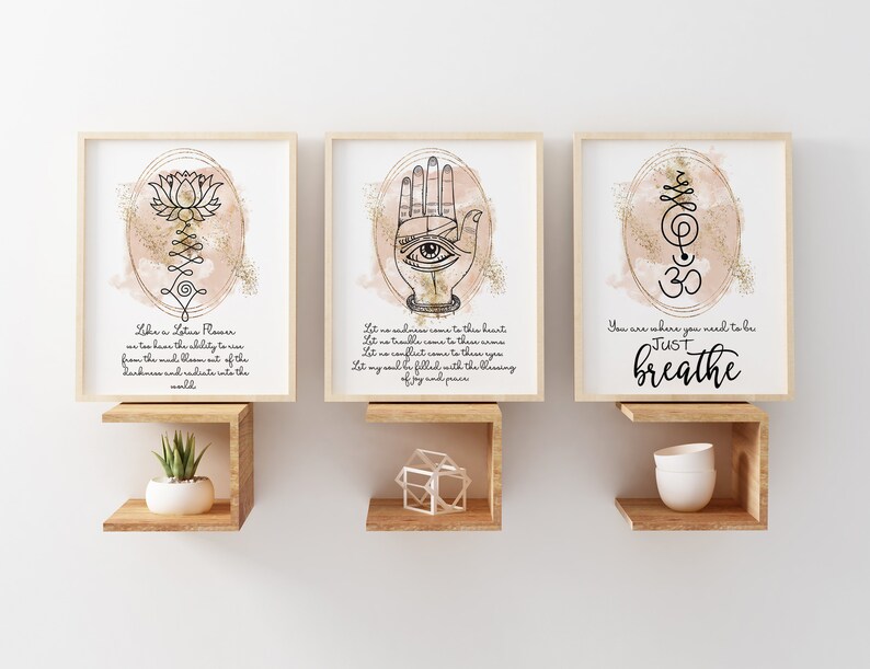 May include: Three framed prints with watercolor backgrounds and gold glitter accents. The first print features a lotus flower with the text "Like a Lotus Flower we too have the ability to rise from the mud, blossom out of the darkness and radiate into the world". The second print features a hand with an eye in the palm and the text "Let no sadness come to this heart, Let no trouble come to this you, Let my soul be filled with the blessing of joy and peace". The third print features a symbol with the text "You are where you need to be, JUST breathe".