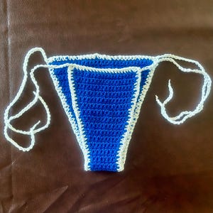 May include: Blue crocheted bikini bottom with white trim and white ties.