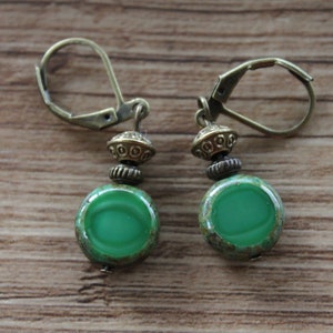 May include: A pair of green glass earrings with bronze accents and leverback closures.