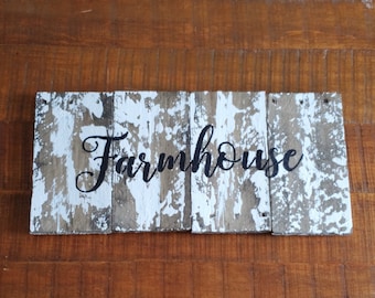 May include: A rustic wooden sign with white paint and the word "Farmhouse" written in black cursive lettering.