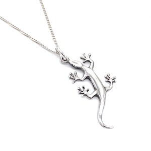 Op de afbeelding: Een zilveren gekko-hangerketting. De gekko is gedetailleerd en heeft een textuur. De ketting is van zilver.