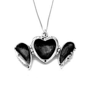 May include: Silver heart-shaped locket necklace with two open wings. The locket is open, revealing the empty interior.