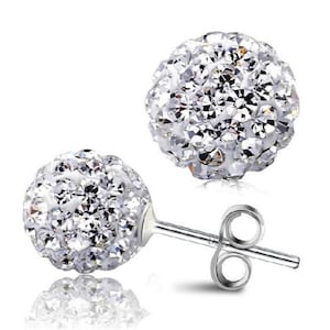 Puede incluir: Un par de pendientes de botón de plata con un diseño redondo y brillante de cristal. Cada pendiente tiene un pequeño poste de plata con un cierre de mariposa.