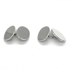 May include: A pair of silver cufflinks with a round, smooth design.