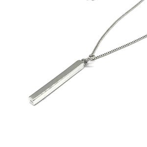 Puede incluir: Un collar de plata con un colgante rectangular largo. El colgante es liso y tiene una superficie ligeramente texturizada.