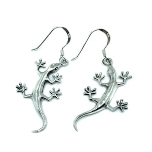 May include: A pair of silver lizard earrings with a detailed design. The earrings are made of sterling silver and have a hook closure.