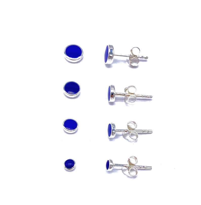 May include: Four pairs of silver stud earrings with blue round stones. The earrings are shown in different sizes.