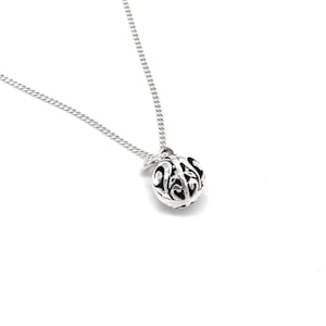 Peut inclure: Un collier en argent avec un pendentif délicat et orné en forme de sphère. Le pendentif présente un motif de filigrane et est attaché à une chaîne en argent.