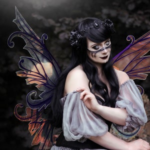 May include: A woman with dark hair and a black crown is wearing a grey dress and large, intricate, iridescent wings. The wings are a mix of orange, purple, and black.