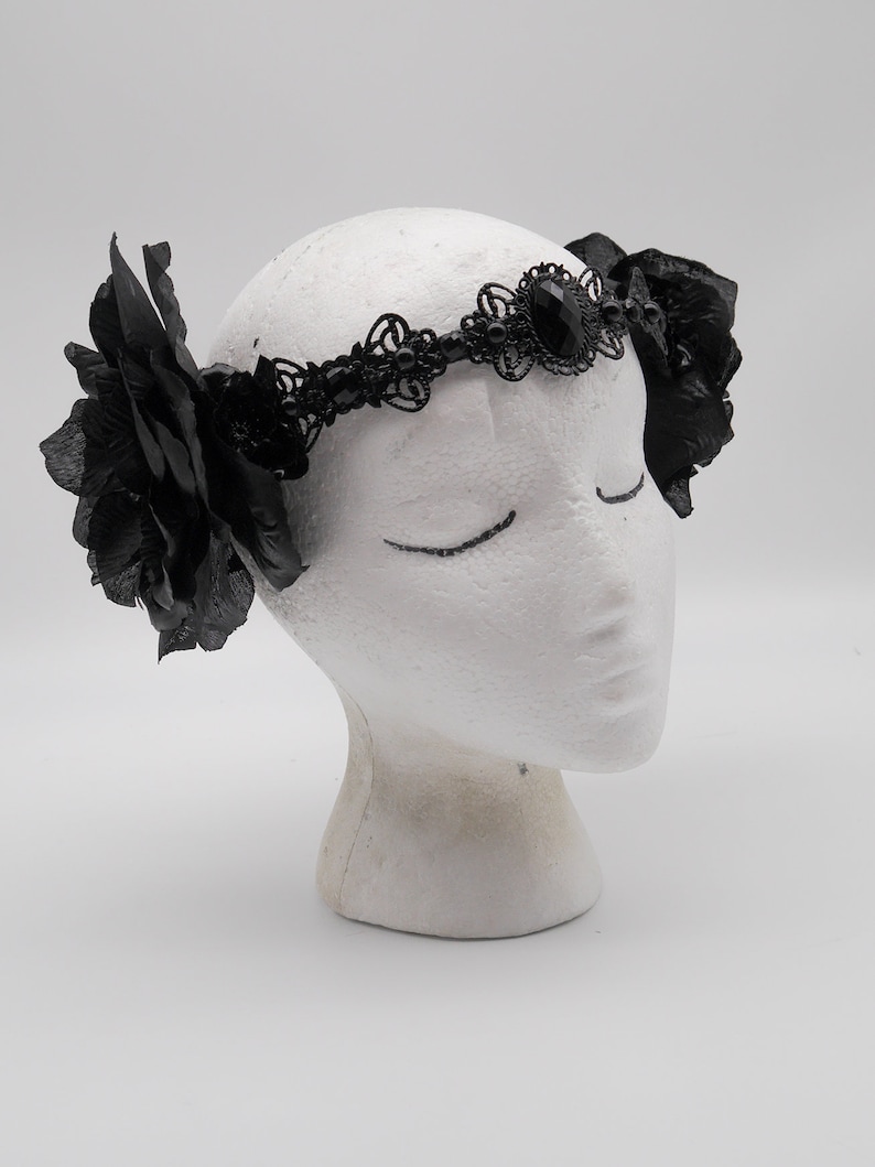 May include: Black lace headband with a large black gemstone and two black fabric roses on either side.