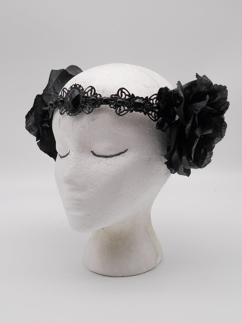 May include: Black lace headband with a large black gemstone and black fabric roses on either side.