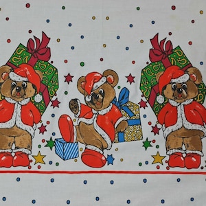 Könnte beinhalten: Ein weißer Stoff mit einem sich wiederholenden Muster aus braunen Teddybären, die rote Weihnachtsmannmützen und Mäntel mit weißem Besatz tragen. Die Bären sind von bunten Geschenken, roten und grünen Sternen sowie kleinen blauen, gelben und roten Punkten umgeben.