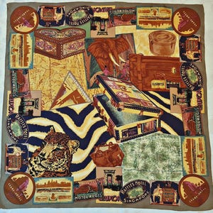 Peut inclure: Un foulard carré présentant un collage d'illustrations sur le thème du voyage, incluant un léopard, un éléphant, des valises vintage, des cartes et diverses étiquettes d'hôtels. Le motif intègre un fond beige avec un motif zébré bleu foncé et jaune.