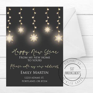 May include: A black and gold New Year's card with a string of lights and snowflakes. The card reads "Happy New Year from my new home to yours. Please note my new address. Emily Martin, 12233 Adams St., Portland, OR 87214."